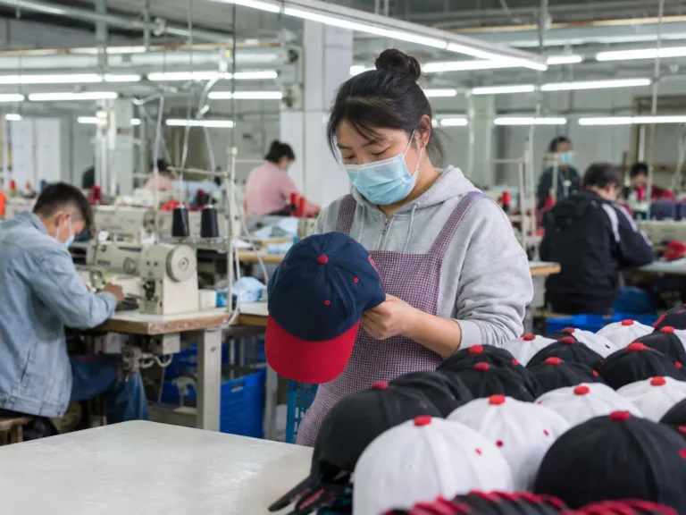 Custom hat production workshop with workers checking caps during bulk manufacturing in a professional cap factory