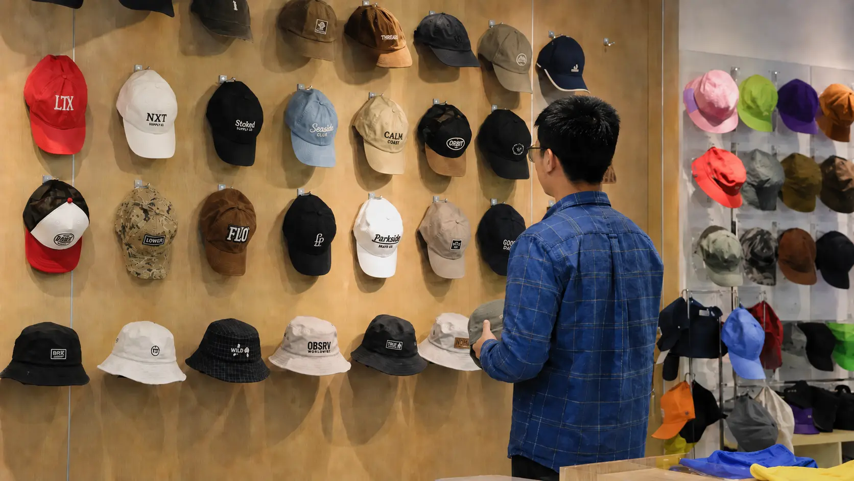 Custom hat sample showroom with baseball caps, bucket hats, dad hats, and trucker hats displayed on the wall
