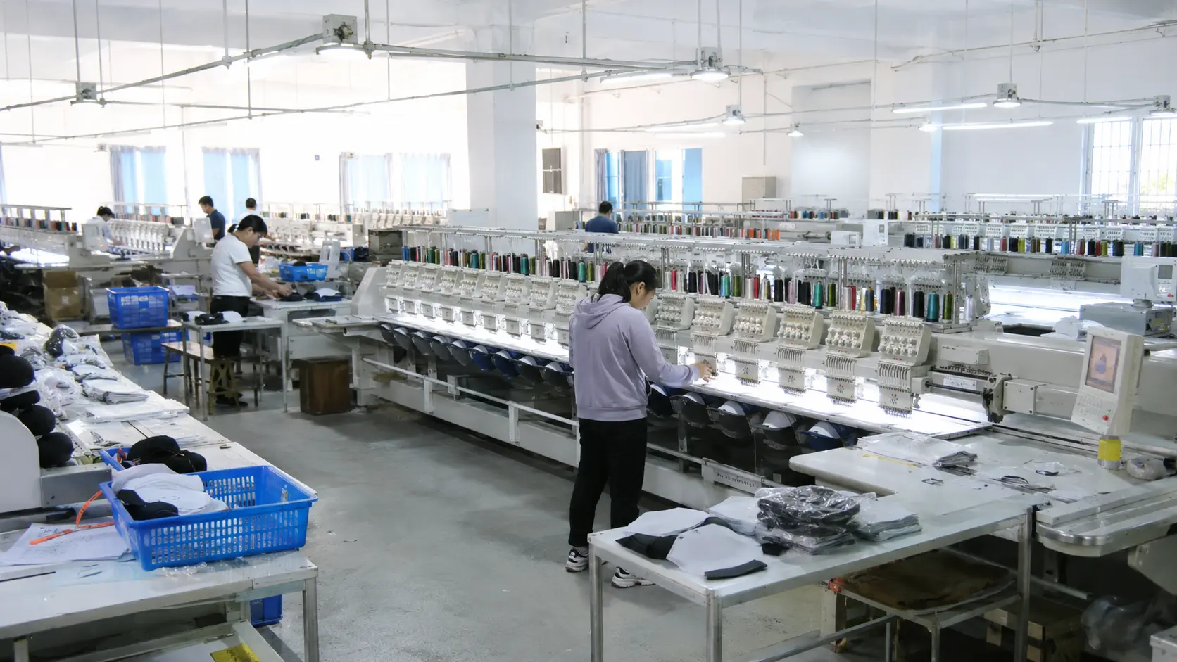 Custom hat embroidery workshop with multi-head embroidery machines producing custom caps in a professional factory